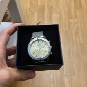 Guldklocka ONE  - En guldklocka märke ONE, man får med en box för klockan. Klockans bandstorlek går att ändra enkelt på klockan