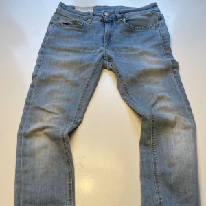 Ljusblå jeans från Dondup, storlek 25 - Snygga ljusblå jeans från Dondup med klassisk femficksdesign och guldfärgade nitar. Jeansen har raka ben och normal passform, med läderpatch bak i midjan och diskret broderi på bakfickorna. Perfekta för en avslappnad stil.