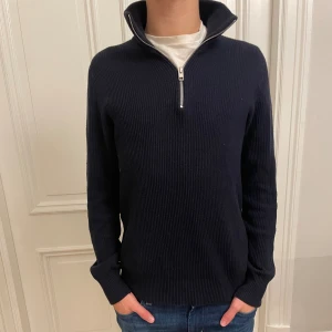 Mörkblå stickad tröja med half zip - Mörkblå stickad tröja med ribbad struktur och hög krage med half zip-dragkedja. Långärmad modell med normal passform, perfekt för kyliga dagar. Enkel och stilren design som funkar till jeans eller chinos. Storleken är xs men är väldigt stor så passar M. 
