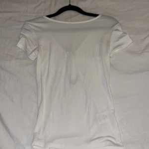 Vit topp med rosett och öppen rygg - Skönt tyg och aldrig använt den. Satin roset där bak.