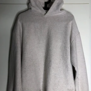 Beige hoodie i mjukt material - Enkel och stilren beige hoodie med huva och lång ärm. Tröjan är i ett mjukt och lite tjockare material, perfekt för kyligare dagar. Oversized passform för en avslappnad look. Passar dig som gillar basic och neutrala färger.