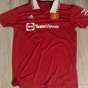 Manchester United matchtröja Adidas L - Röd Manchester United fotbollströja från Adidas med vit krage och svarta detaljer. Köpt på unisports 