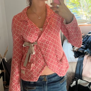 Rosa stickad cardigan jacka Odd Molly - Superfin rosa och vit stickad cardigan jacka från Odd Molly med rutig mönster, knytband i midjan och broderad detalj på ärmen. Jackan har en omlottmodell och långa ärmar, perfekt för dig som gillar en mysig och snygg stil.