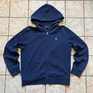 Marinblå zip hoodie från Polo Ralph Lauren size S  - Marinblå zip hoodie från Polo Ralph                   - Längd (63cm) bredd (52cm) ärm (61cm)         - 9/10 skick, använd nån gång, ett pyttelitet hål vid ärmen som inte syns                                      Pris och bilder går o diskutera 🫡