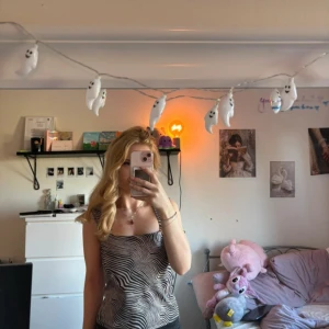 Zebramönstrad linnetopp från Vero Moda - Säljer en snygg zebramönstrad linnetopp från Vero Moda i svart och beige. Toppen är ärmlös med raka axelband och har en loose passform. Perfekt för dig som vill sticka ut med ett coolt mönster och mjukt material.