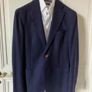 Blazer mörkblå från Rose&Born  - Sparsamt använd blazer från Rose&Born. Två fickor, breda slag, ofodrad, 100% virgin ull.