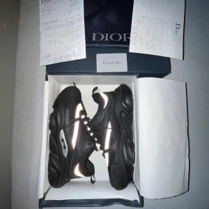 Svarta sneakers med reflex - Säljer ett par svarta CD sneakers med chunky sula och coola reflexdetaljer. Skorna har snörning, meshpaneler och detaljer i syntet och skinn. Märkeslogga på sidan och innersulan. Kommer med originalkartong och dustbag.