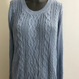 Ljusblå stickad tröja från Lindex - Superskön ljusblå stickad tröja från Lindex med klassiskt flätmönster framtill. Rund halsringning, långa ärmar och ribbade muddar. Perfekt för lager-på-lager och chill dagar.