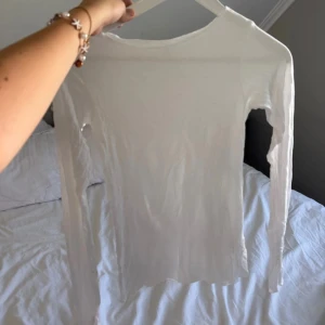 Vit långärmad topp från Stories XS - Enkel och stilren vit långärmad topp från Stories i storlek XS. Tunn och lätt i materialet, perfekt att styla med jeans eller kjol. Klassisk rund halsringning och figurnära passform som ger en clean look. Lik märker intimissimi