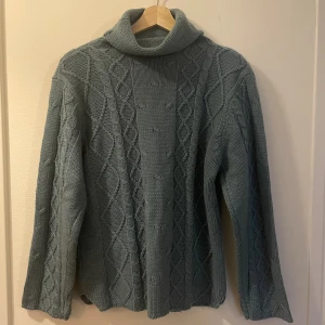Blå stickad polotröja  - Mysig blå stickad polotröja från Peppercorn med kabelstickat mönster och bred krage. Tröjan har lång ärm och en relaxed fit, perfekt för kyliga dagar. Har använts sparsamt. 