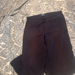 Mörkblåa linnebyxor med snörning - Svarta linnebyxor med avslappnad passform och snörning i midjan. Byxorna har resår bak och fickor fram samt en bakficka. Perfekta för en chill och stilren look.