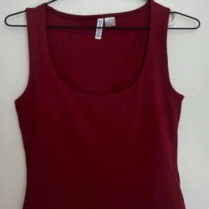 Vinröd ärmlös klänning från H&M - Snygg vinröd klänning från H&M med ärmlös design och rundad halsringning. Enkel och stilren modell som sitter fint på kroppen. Perfekt för dig som gillar minimalistisk stil och vill ha en klänning som sticker ut med sin djupa färg.