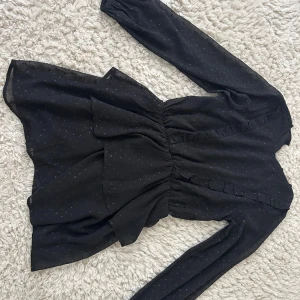 Svart kortklänning med volang - Supersöt svart kortklänning med glittriga små prickar och volangdetaljer. Passar perfekt till nyår!