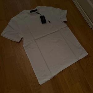 Vit Ralph Lauren T-shirt - Säljer en vit t-shirt från Ralph Lauren. Storlek M. Den är i helt nytt skick med tagg kvar. Skickas i originalförpackningen!  Nypris: 800kr   