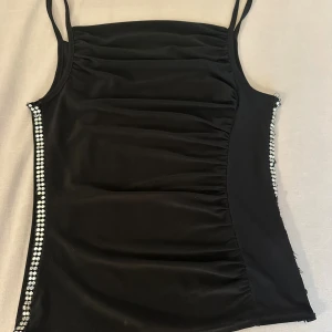 Svart glittrig linnetopp med strass - French black tank top with rhinestones on the sides  Missing some rhinestones  Kolla gärna på mina andra mina andra annonser