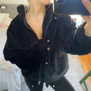 Svart teddyjacka med dragkedja (pälsjacka) - Mysig svart teddyjacka med hög krage och dragkedja framtill. 