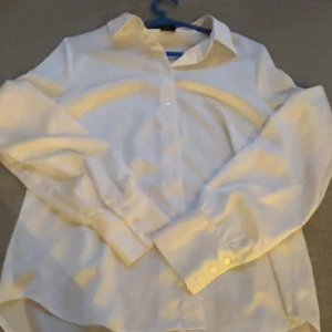 Vit skjorta från Gina Tricot - Klassisk vit siden skjorta från Gina Tricot i storlek 38. Skjortan har lång ärm, knappar framtill och klassisk krage. Perfekt för en clean och stilren look. Tillverkad i ett mjukt material som känns skönt mot huden.