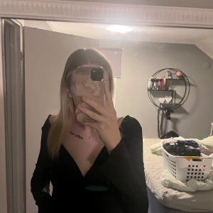 Svart långärmad topp med öppen rygg - Säljer en svart långärmad topp med djup v-ringning och snygg öppen rygg med knyt bak. Toppen har en elegant och stilren look, perfekt för dig som vill sticka ut. Materialet känns mjukt och följsamt mot kroppen.