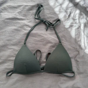 Mörkgrön bikiniöverdel från H&M - Snygg mörkgrön bikiniöverdel från H&M i klassisk triangelmodell. Den har smala band som knyts i nacken och runt ryggen. Tillverkad i mjukt syntetmaterial som torkar snabbt. Storlek 36/S och bra skick!🤗