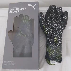 Puma målvaktshandskar Future Ultimate - Snygga målvaktshandskar från Puma i modellen Future Ultimate Rush NC. De är mörkgrå med vita prickar och detaljer i limegrönt. Handskarna har 4mm Elite+ Dual Grip för extra grepp och stickad mudd för skön passform. Perfekta för dig som vill sticka ut på fotbollsplanen.