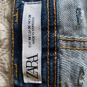 Blå raka jeans från Zara - Säljer ett par klassiska blå jeans från Zara med raka ben och normal passform. Jeansen har fem fickor, snygga kontrastsömmar och är tillverkade i ett tåligt denimtyg. Perfekta för en avslappnad och stilren look.