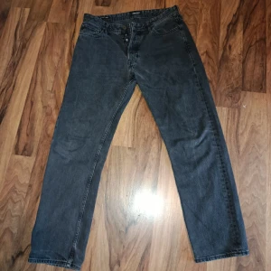 Svarta relaxed jeans Jack & Jones 32/32 - Svarta jeans från Jack & Jones i relaxed fit med raka ben och klassisk femficksdesign. Jeansen är tillverkade i denim och har knappgylf. Perfekta för dig som gillar en lite behaglig passform och enkel stil. Inga skador men använda på ett bra sätt.