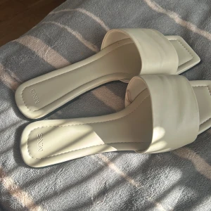 Beige sandaler från Mango med fyrkantig tå - Snygga beige sandaler från Mango med bred rem och fyrkantig tå. Platt sula och stilren design i syntetmaterial, perfekta för varma dagar. Minimalistisk look som passar till allt och ger en clean vibe. De kommer i boxen 