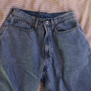 Blå jeansshorts från Vailent  - Säljer ett par klassiska blå jeansshorts från Vailent i storlek XS. Modellen har hög midja, raka ben och fem fickor. Jeansen är tillverkade i slitstarkt bomullsjeansmaterial och har dragkedja och knapp framtill. Perfekt för dig som gillar en tidlös och chill look. Jätte sköna att ha på sig om du är ute eller om du bara chillar hemma. 