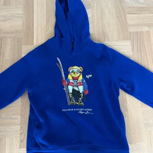Ralph lauren hoodie polo bear  - Blå hoodie från Polo Ralph Lauren med ikoniskt Polo Bear-tryck framtill. Tröjan har huva och är tillverkad i mjuk bomull. Inga defekter, priset är inte hugget i sten. 