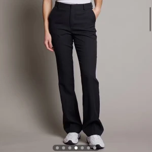 Svarta kostymbyxor med medelhög midja - Stilrena svarta kostymbyxor med medelhög midja och raka ben. Byxorna har pressveck, hällor för bälte och diskreta bakfickor. Säljer dessa Vilma kostymbyxor från BIK BOK fint skick säljes för 150kr