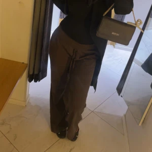 Bruna vida byxor med snörning - Snygga bruna byxor med vida ben och snörning i midjan. Perfekta för en chill och avslappnad look. Byxorna har en loose passform och är tillverkade i ett mjukt material som känns skönt mot huden.