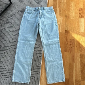 Ljusblå raka jeans i storlek 42 - Ljusblå jeans med klassisk femficksdesign och raka ben. Jeansen har normalhög midja och stängs med dragkedja och knapp. Tillverkade i denim med snygg tvättad look, perfekta för en avslappnad stil.