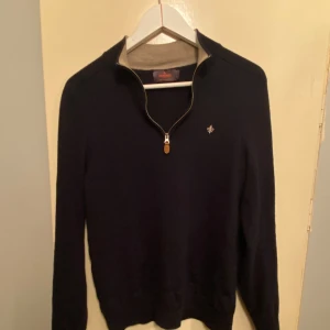 Mörkblå merinoullströja Morris - Snygg mörkblå tröja från Morris i 100% merinoull. Tröjan har half zip-dragkedja med läderdetalj och liten broderad logga på bröstet. Perfekt för dig som gillar stilrena och klassiska plagg med premiumkänsla. Står att de ä l men den sitter som S 
