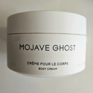 Byredo Mojave Ghost Body Cream - Lyxig body cream från Byredo i doften Mojave Ghost. Kommer i en stilren vit rund burk. Krämen är vit och har en mjuk, krämig konsistens. Perfekt för dig som gillar exklusiva dofter och vill ha en återfuktande kroppskräm med elegant design.