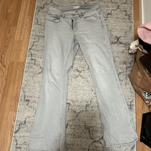 Ljusgrå bootcut jeans från Gina Tricot Perfect Jeans - Säljer ett par ljusgrå jeans från Perfect Jeans i storlek 42. Modellen har bootcut-ben och klassisk femficksdesign. Jeansen är tillverkade i mjukt denimtyg och har normal passform med dragkedja och knapp framtill.