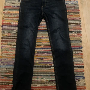 Levi's 512 Slim Taper jeans mörkblå - Storlek 16A i junior vilket motsvarar W28/L30 Mörkblå Levi's 512 Slim Taper jeans med klassiska gula sömmar och femficksdesign. Jeansen har en smal passform med avsmalnande ben och är tillverkade i slitstarkt denim. Perfekta för dig som gillar en modern och stilren look.