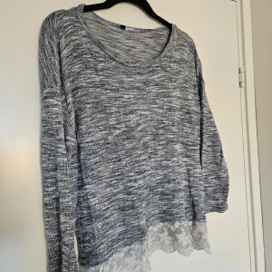 Blå stickad tröja med spetskant - Supermysig gråblå stickad tröja med rund halsringning och lång ärm. Nedtill finns en snygg vit spetskant med blommönster. Lappen är bortklippt men skulle säga den passar S. Köpt på H&M 