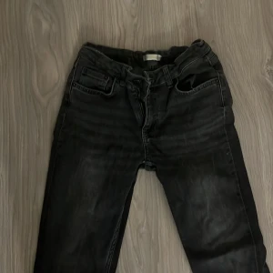 Svarta jeans från Gina Tricot - Snygga svarta jeans från Gina Tricot med klassisk femficksdesign och dragkedjegylf. Jeansen har en något tvättad look och raka ben. Perfekta för dig som gillar en stilren och enkel vibe.