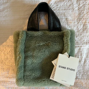 Grön pälsväska från Stand Studio - 💚Modell: Lucille Bag  💚Nypris: ca. 2800kr  💚Material: Fuskpäls i ullblandning samt handtag och axelband i konstläder.  💚Avtagbart axelband: 110 cm inklusive spännen.  💚Helt oanvänd med lappar, dustbag och skyddsplast kvar!