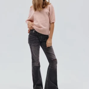 Svarta bootcut jeans med slitningar - Snygga svarta bootcut jeans med slitningar på knäet och stora framfickor. Jeansen har låg midja och en lätt tvättad look som ger en cool vintagekänsla. Perfekta för dig som gillar en avslappnad och trendig stil. Storlek 158-164