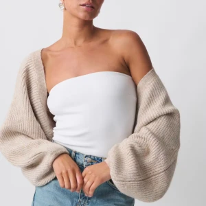 Beige stickad bolerotopp från Gina Tricot - Säljer en beige stickad bolerotopp från Gina Tricot med oversized ärmar och ribbad struktur. Toppen har en öppen design utan knäppning och är perfekt att slänga över en bandeau eller linne för en chill look🩷