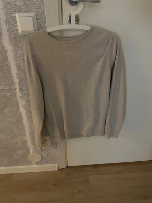 Beige långärmad tröja från Kappahl - En enkel och stilren beige långärmad tröja från Kappahl i storlek S. Tröjan har rund halsringning och är gjord i mjuk bomull, perfekt för chill dagar eller när du vill ha en clean look. Passformen är normal och den är lätt att matcha med jeans eller 
