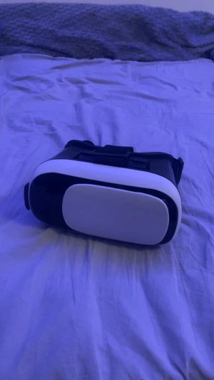 VR-headset  - Upplev virtuell verklighet med detta VR-headset. Man har mobilen i den och kan köra karuseller eller titta på olika häftiga saker. Justerbara linser och bekväma remmar. Fungerar med de alla mobiltelefoner som jag har testat med iallafall för att den är justerbar så att man kan göra den större! Svart och vit design, i gott skick utan synligt slitage. Perfekt för spel och 360-video. Bra pris och använd 2-3 gånger 
