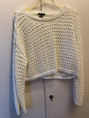 Vit stickad croppad tröja Massimo Dutti -  stickad tröja från Massimo Dutti med coolt hålmönster och croppad passform. Tröjan har långa ärmar och bred ribbad kant vid hals, ärmslut och nederkant. Storlek S