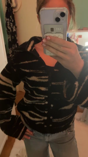 Zebramönstrad kofta i svart och beige XS - Säljer en fluffig och mysig kofta med zebramönster i svart och beige. Koftan har dragkedja framtill, krage och långa ärmar. . Perfekt för dig som gillar djurmönster och vill sticka ut lite extra. Bra skick bara lite nopprig på insidan se bild❤️