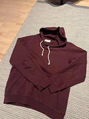 Vinröd hoodie från Pier One - Säljer en vinröd hoodie från Pier One med vit snörning i huvan och klassisk känguruficka framtill. 