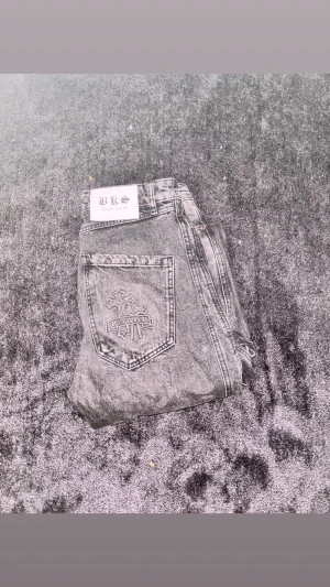 Svarta Y2K jeans med broderad bakficka - Säljer ett par svarta jeans från BKS Black Squad med broderad detalj på bakfickan. Jeansen har en rak passform och klassisk femficksdesign. Materialet är denim och färgen är tvättad svart med slitna detaljer för en cool Y2Klook.