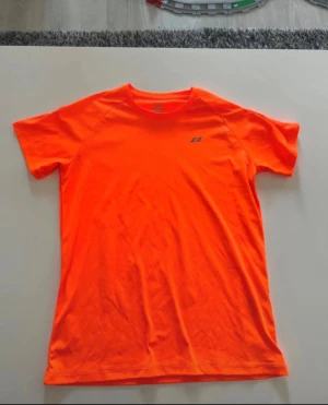Neonorange tränings-tshirt från Dobsom - Säljer en neonorange t-shirt från Dobsom med korta ärmar och rund hals. Perfekt för träning med sitt lätta och ventilerande polyestermaterial. Diskret logga på bröstet. Snygg och sportig look som sticker ut på gymmet eller löprundan.