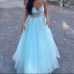 Ljusblå balklänning 🩵🩵🩵 - Drömmig ljusblå långklänning med v-ringad urringning och tunna axelband. Klänningen har glittriga detaljer och vacker spets upptill, samt en vid kjol i flera lager Perfekt för bal! Materialet känns som mjuk polyester med inslag av glitter.