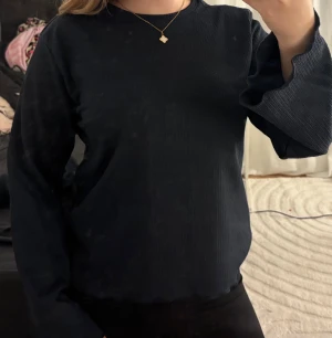 Mörkblå ribbad långärmad tröja - Säljer en mörkblå långärmad tröja med ribbad struktur och lätt utsvängda ärmar. Tröjan har en enkel rund halsringning och är gjord i ett mjukt material som sitter snyggt på kroppen. Perfekt för dig som gillar stilrena och bekväma plagg.